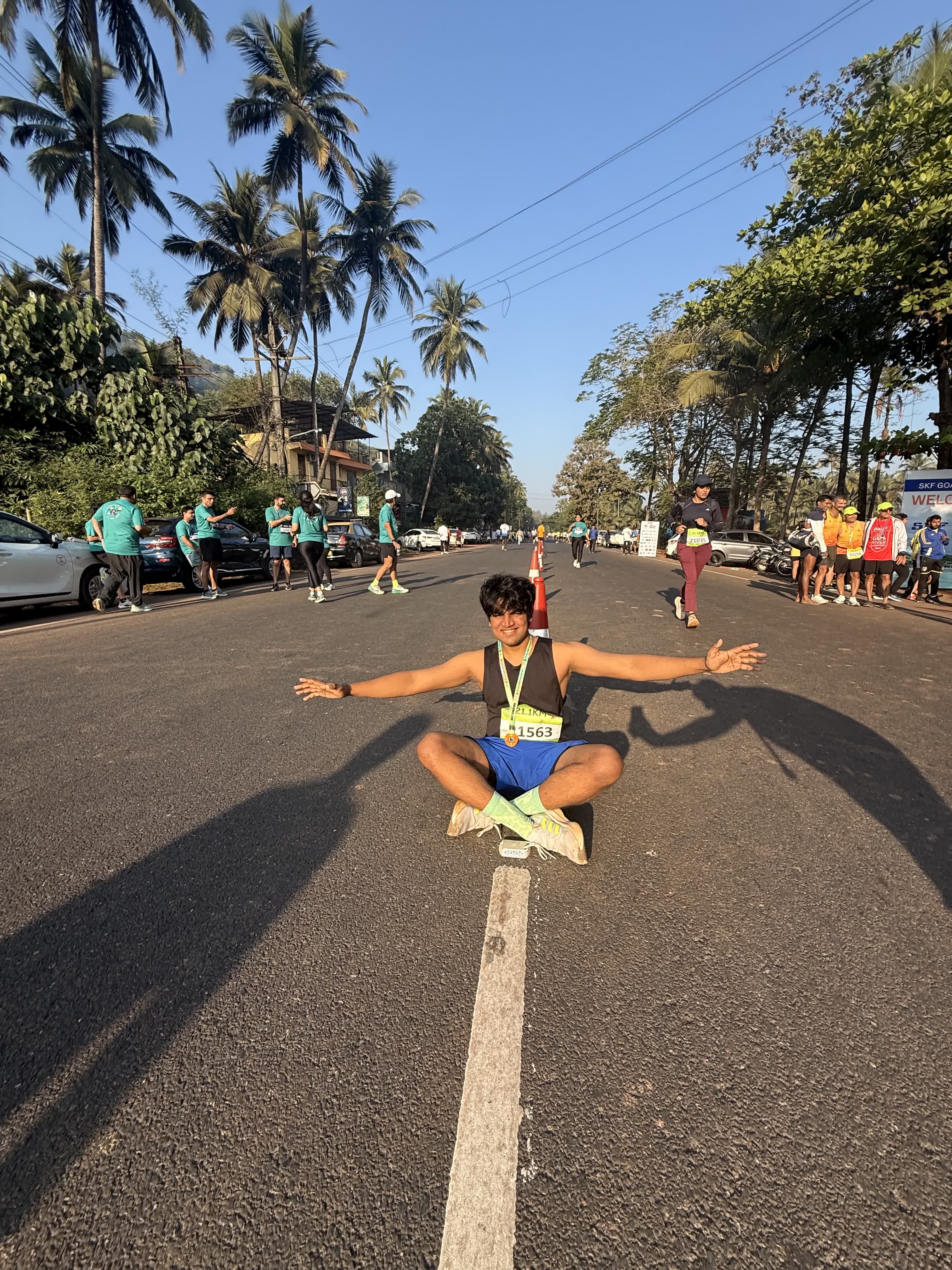 Sitting arms-wide in the middle of a palm-lined road after the half marathon, race bib on