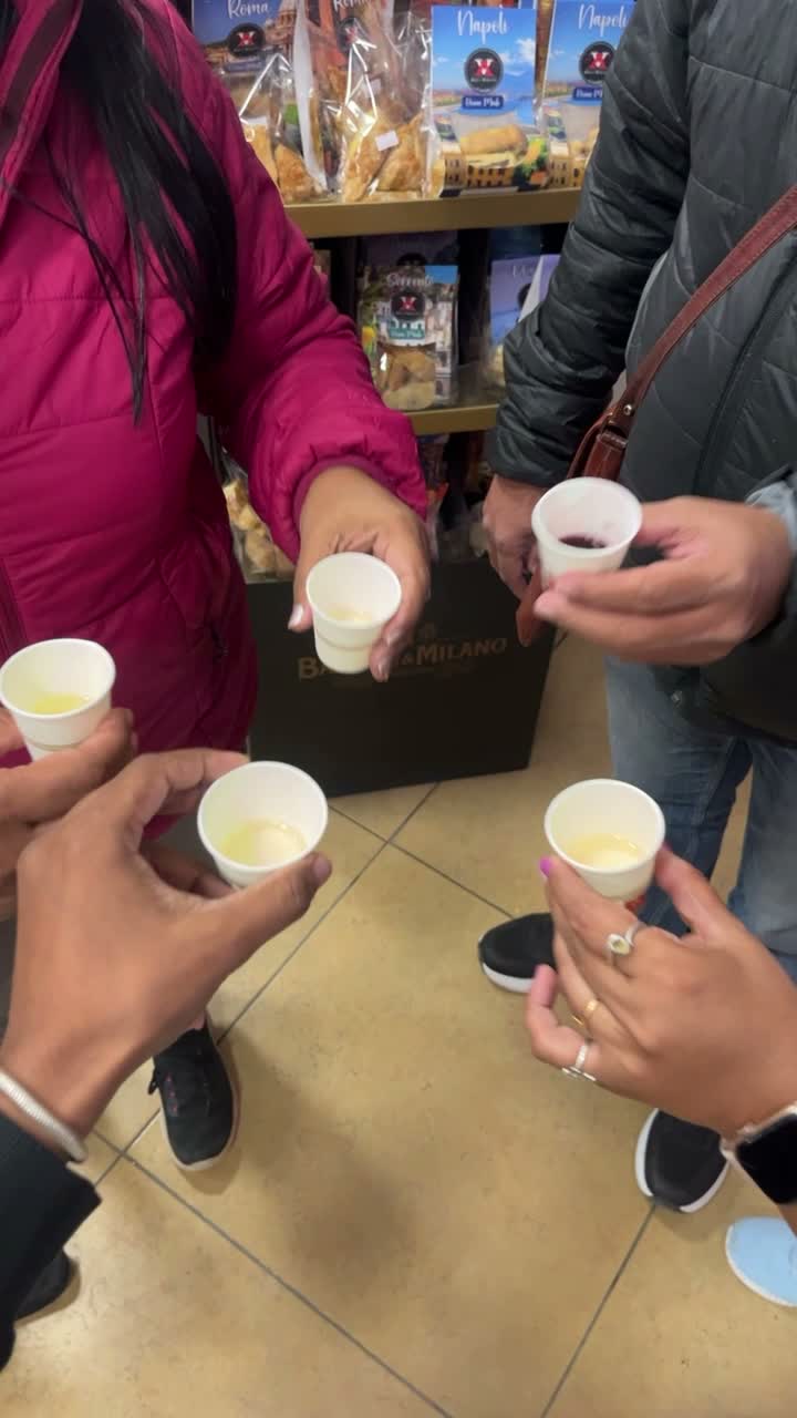 A group toasting with small cups of limoncello in a shop